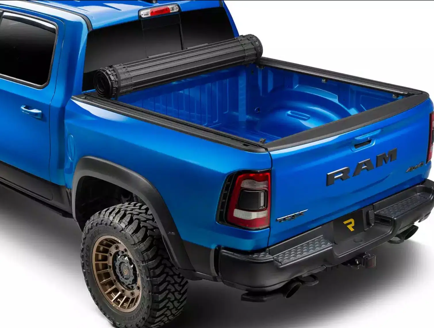 A BAK Revolver X4s hard roll-up tonneau cover closed over the bed of a blue Ram TRX