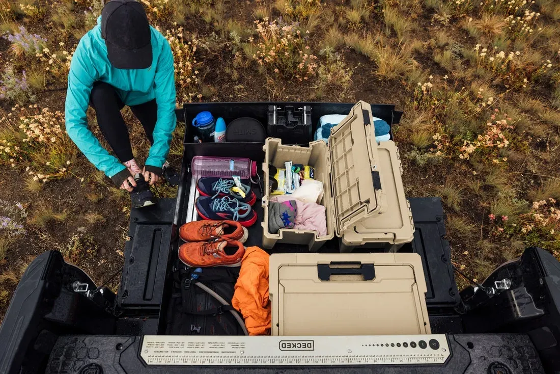 Looking down into a truck bed with DECKED drawers open, holding cases, straps and gear (DECKED photo)