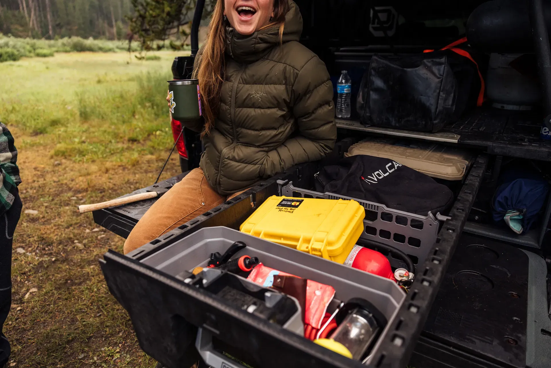 A woman laughing beside an open DECKED drawer packed with camp gear (DECKED photo)