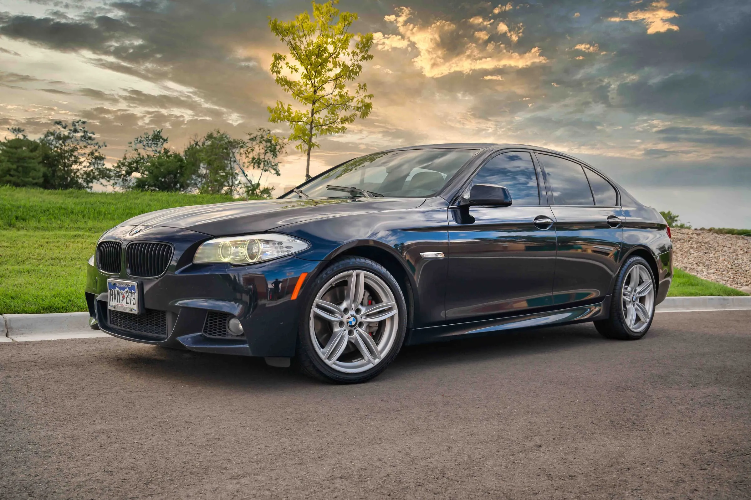 A dark blue BMW 5 Series parked outdoors at sunset after a full detail