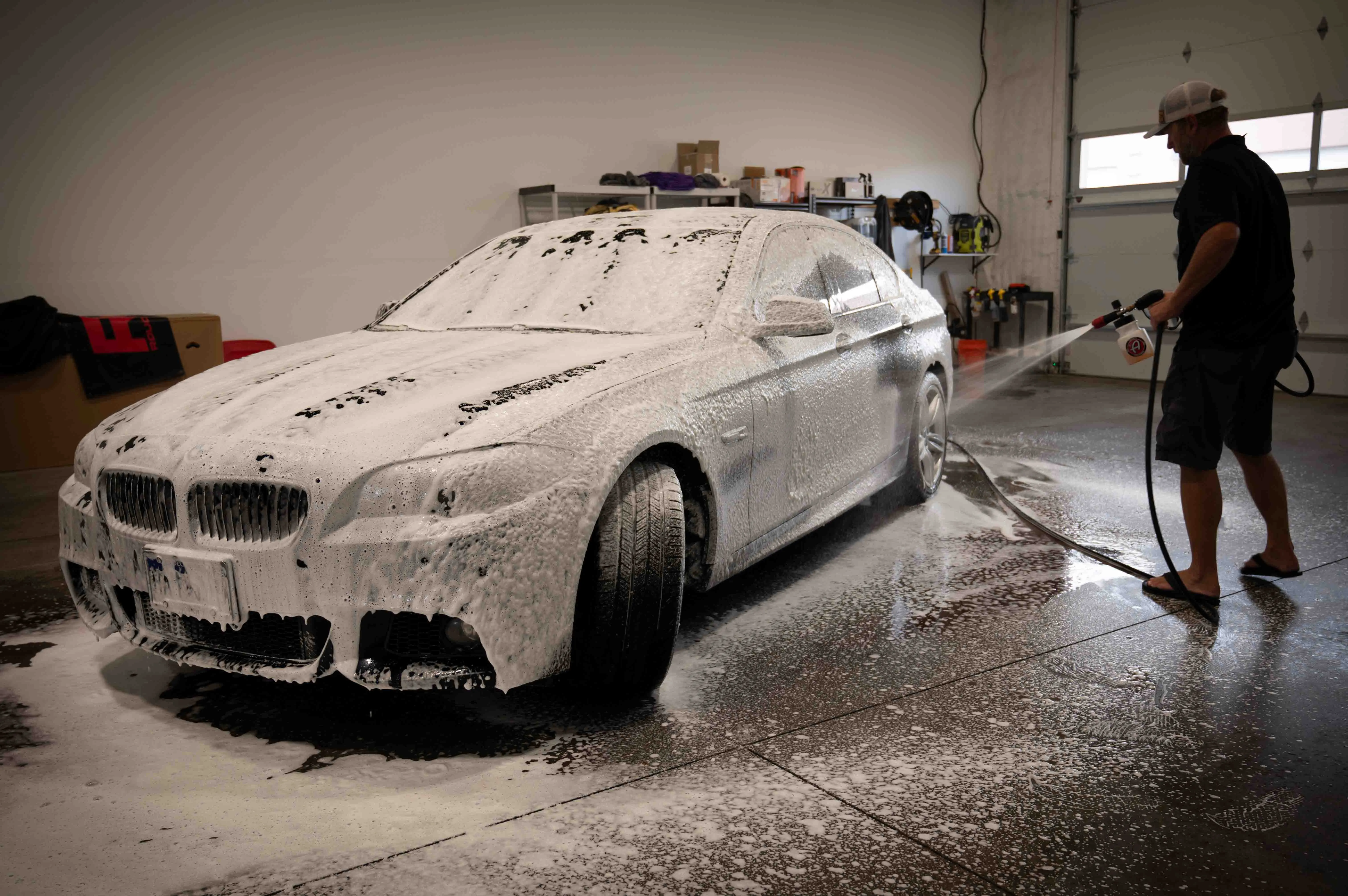 BMW covered in snow foam inside the wash bay