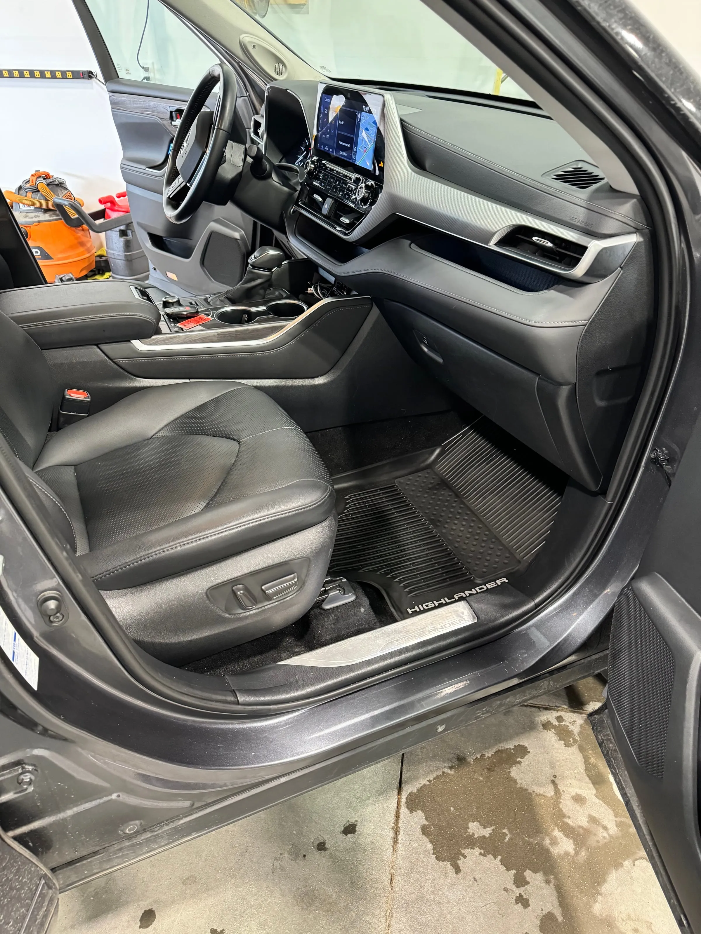The driver's door of a Toyota Highlander open on a cleaned interior, the sill and floor mats freshly detailed
