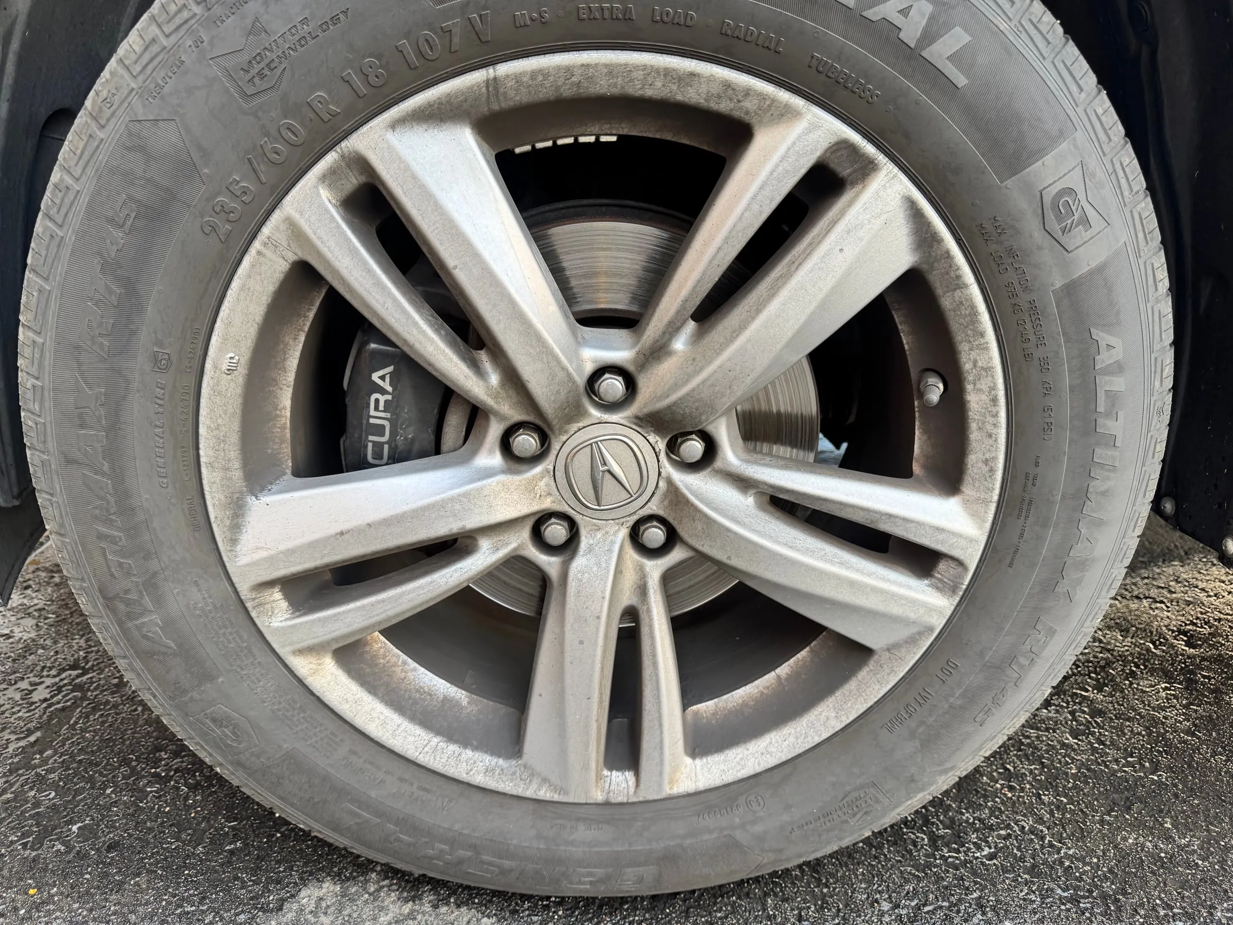 An Acura alloy wheel caked in brake dust before cleaning