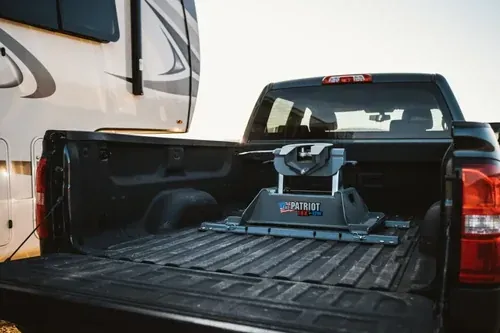A 5th wheel hitch mounted in the bed of a black pickup (B&W photo)