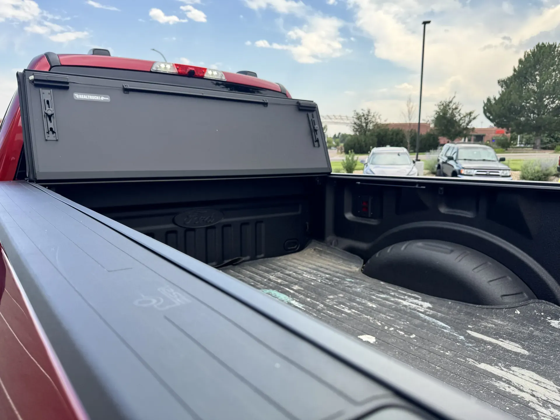 A BAKFlip MX4 folded toward the cab on a red Ford F-250, showing the open bed, at Ride N' Shine