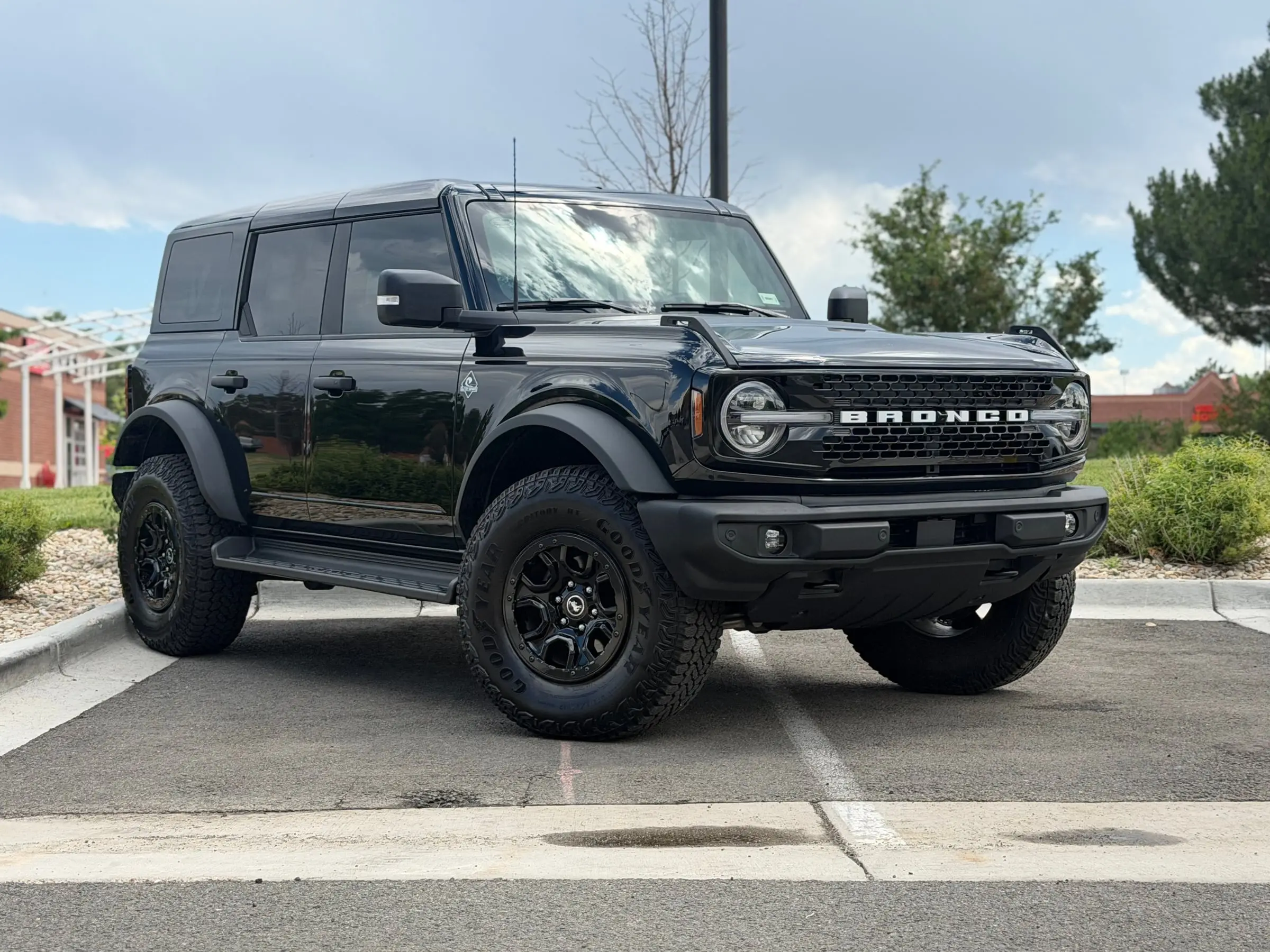 A black four-door Ford Bronco with fresh front paint protection film parked outside the shop