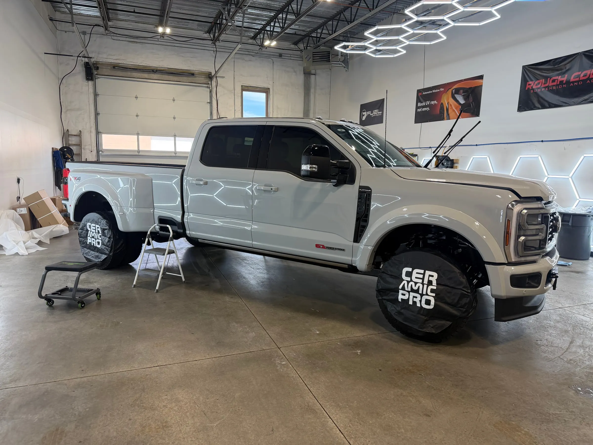 A lifted grey Ford Super Duty dually with a 6.7 Power Stroke badge under the studio's hexagon lights