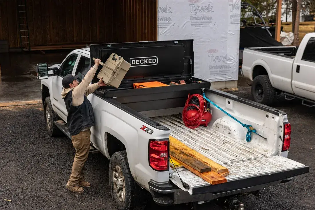 A man lifting a case out of a DECKED Tool Box on a white Chevrolet Silverado (DECKED photo)