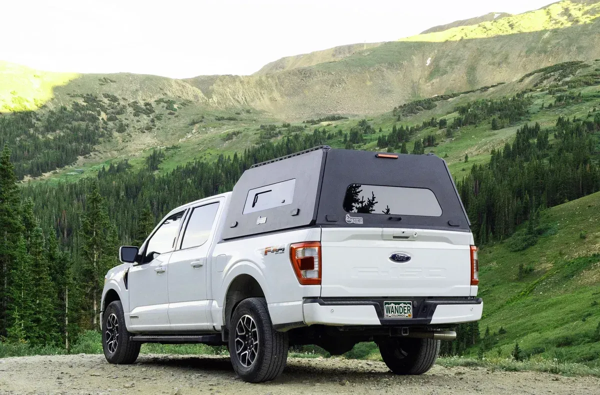 A white Ford F-150 with a WanderFox Super Den XL topper on a mountain road (WanderFox photo)