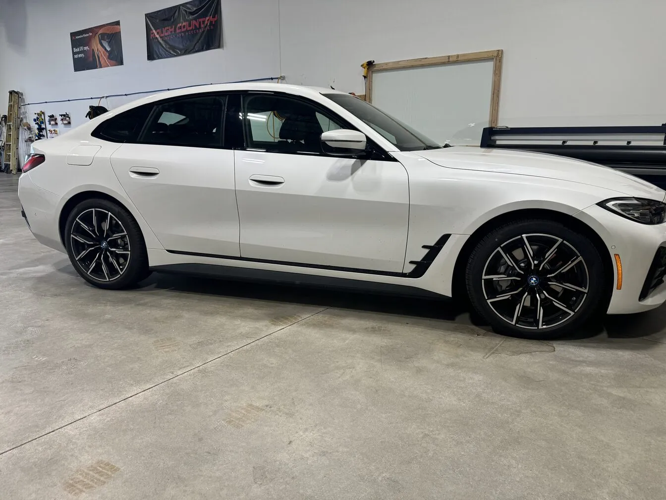 White BMW 4 Series Gran Coupe inside the studio beside a glass work panel